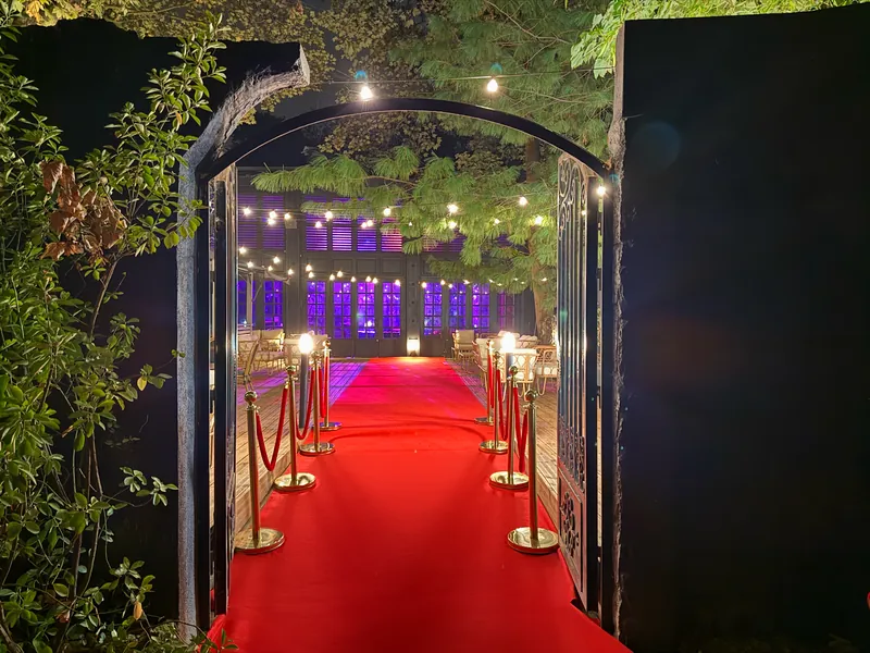 Portail ouvert et tapis rouge donnant sur la terrasse illuminée de Maya